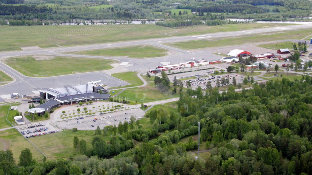 Flygfoto över Sundsvall-Timrå flygplats med landningsbana, terminalbyggnad, parkering och omgivande skog